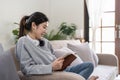 Young beautiful asian woman student sitting on sofa reading book at home. Royalty Free Stock Photo