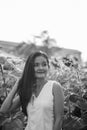 Young beautiful Asian woman thinking while fixing hair in the field of blooming sunflowers Royalty Free Stock Photo