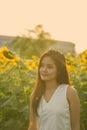 Young beautiful Asian woman thinking while looking at distance in the field of blooming sunflowers Royalty Free Stock Photo