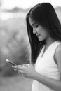 Young beautiful Asian woman using mobile phone against field of blooming sunflowers Royalty Free Stock Photo