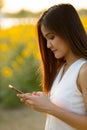 Young beautiful Asian woman using mobile phone against field of Royalty Free Stock Photo