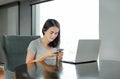 Young beautiful asian woman using mobile phone and laptop computer working online at home and feel relaxing on armchair Royalty Free Stock Photo