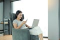 Young beautiful asian woman using mobile phone and laptop computer working online at home and feel relaxing on armchair Royalty Free Stock Photo