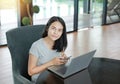 Young beautiful asian woman using mobile phone and laptop computer working online at home and feel relaxing on armchair Royalty Free Stock Photo