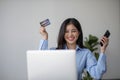 Young beautiful Asian woman using smartphone and credit card for online shopping at home with copy space. E-payment Royalty Free Stock Photo