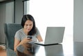 Young beautiful asian woman using smartphone and laptop computer working online at home and feel relaxing on armchair. People Royalty Free Stock Photo