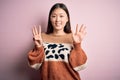 Young beautiful asian woman wearing animal print fashion sweater over pink isolated background showing and pointing up with