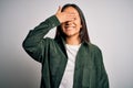 Young beautiful asian woman wearing casual shirt standing over isolated white background smiling and laughing with hand on face Royalty Free Stock Photo