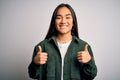 Young beautiful asian woman wearing casual shirt standing over isolated white background success sign doing positive gesture with Royalty Free Stock Photo