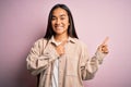 Young beautiful asian woman wearing casual shirt standing over pink background smiling and looking at the camera pointing with two Royalty Free Stock Photo