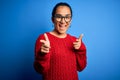 Young beautiful asian woman wearing casual sweater and glasses over blue background pointing fingers to camera with happy and Royalty Free Stock Photo