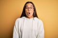 Young beautiful asian woman wearing casual sweater and glasses over yellow background afraid and shocked with surprise expression, Royalty Free Stock Photo