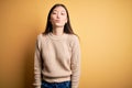 Young beautiful asian woman wearing casual sweater over yellow isolated background looking at the camera blowing a kiss on air Royalty Free Stock Photo