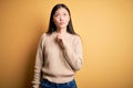 Young beautiful asian woman wearing casual sweater over yellow isolated background Thinking concentrated about doubt with finger