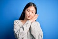 Young beautiful asian woman wearing casual sweater standing over blue isolated background sleeping tired dreaming and posing with Royalty Free Stock Photo