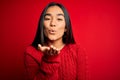 Young beautiful asian woman wearing casual sweater standing over isolated red background looking at the camera blowing a kiss with Royalty Free Stock Photo