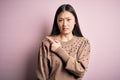 Young beautiful asian woman wearing fashion and elegant sweater over pink solated background Pointing aside worried and nervous