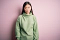 Young beautiful asian woman wearing green winter sweater over pink solated background depressed and worry for distress, crying