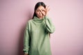 Young beautiful asian woman wearing green winter sweater over pink solated background doing ok gesture shocked with surprised Royalty Free Stock Photo