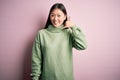 Young beautiful asian woman wearing green winter sweater over pink solated background smiling doing phone gesture with hand and Royalty Free Stock Photo