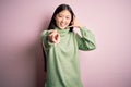 Young beautiful asian woman wearing green winter sweater over pink solated background smiling doing talking on the telephone Royalty Free Stock Photo