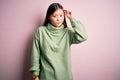 Young beautiful asian woman wearing green winter sweater over pink solated background worried and stressed about a problem with