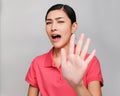 Young beautiful asian woman wore pink t shirt, Raise her hand,Showed prohibit expression , on gray background