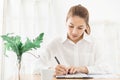 Young Beautiful asian woman wore white shirt Sit and write a book,work at home