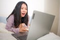 Young beautiful Asian woman working with laptop on bed -  lifestyle home portrait of young pretty and happy Korean student girl Royalty Free Stock Photo