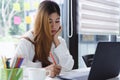 Young beautiful asian woman working with laptop and writing on notebook in co-space working or cafe. Financial and accounting conc Royalty Free Stock Photo