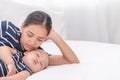 Young beautiful Asian women laying down with her baby in bed, Mother looking her bab sleeping.  Mother happy takes care of her son Royalty Free Stock Photo