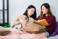 Young beautiful Asian women lesbian couple lover reading book and playing cute cat pet in living room at home with smiling face. Royalty Free Stock Photo