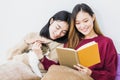 Young beautiful Asian women lesbian couple lover reading book and playing cute cat pet in living room at home with smiling face. Royalty Free Stock Photo