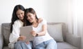 Young beautiful Asian women lesbian couple lover using tablet video call online in living room on sofa at home with smiling face. Royalty Free Stock Photo