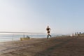 Young beautiful athletic girl with long blond hair in black clothes running at sunrise over the sea Royalty Free Stock Photo