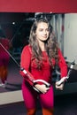 Young beautiful athletic girl trains on the simulator in the gym. sporty woman in red leggings doing exercise Royalty Free Stock Photo