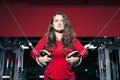 Young beautiful athletic girl trains on the simulator in the gym. sporty woman in red leggings doing exercise Royalty Free Stock Photo