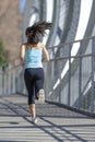 Young beautiful athletic sport woman running and jogging crossing modern metal city bridge