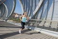 Young beautiful athletic sport woman running and jogging crossing modern metal city bridge Royalty Free Stock Photo