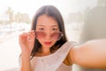 Young beautiful and attractive Asian Chinese woman taking selfie with mobile phone in cool sunglasses posing outdoors on a sunny Royalty Free Stock Photo