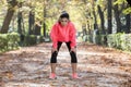 Attractive sport woman in runner sportswear breathing gasping and taking a break tired and exhausted after running workout on Autu