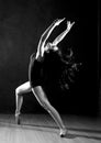 Young beautiful ballet dancer in pointe shoes, dancing in a dark background. black and white