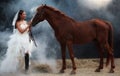 Young beautiful beauty bride in fashion white wedding costume stand with handsome horse on black background Royalty Free Stock Photo