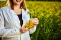 A young beautiful biologist or agronomist examines the quality of rapeseed oil on a rape field. Agribusiness concept Royalty Free Stock Photo