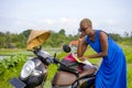 Young beautiful black afro american tourist woman with scooter motorbike looking to road map searching the way exploring fields in Royalty Free Stock Photo