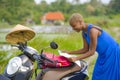 Young beautiful black afro american tourist woman with scooter motorbike looking to road map searching the way exploring fields in Royalty Free Stock Photo