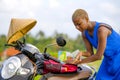 Young beautiful black afro american tourist woman with scooter motorbike looking to road map searching the way exploring fields in Royalty Free Stock Photo