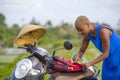 Young beautiful black afro american tourist woman with scooter motorbike looking to road map searching the way exploring fields in Royalty Free Stock Photo