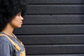 Young pretty afro girl profile with curly hair standing on black wall background.