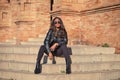 young and beautiful black latin woman wearing black clothes and sunglasses is sitting on the steps of the most important square in